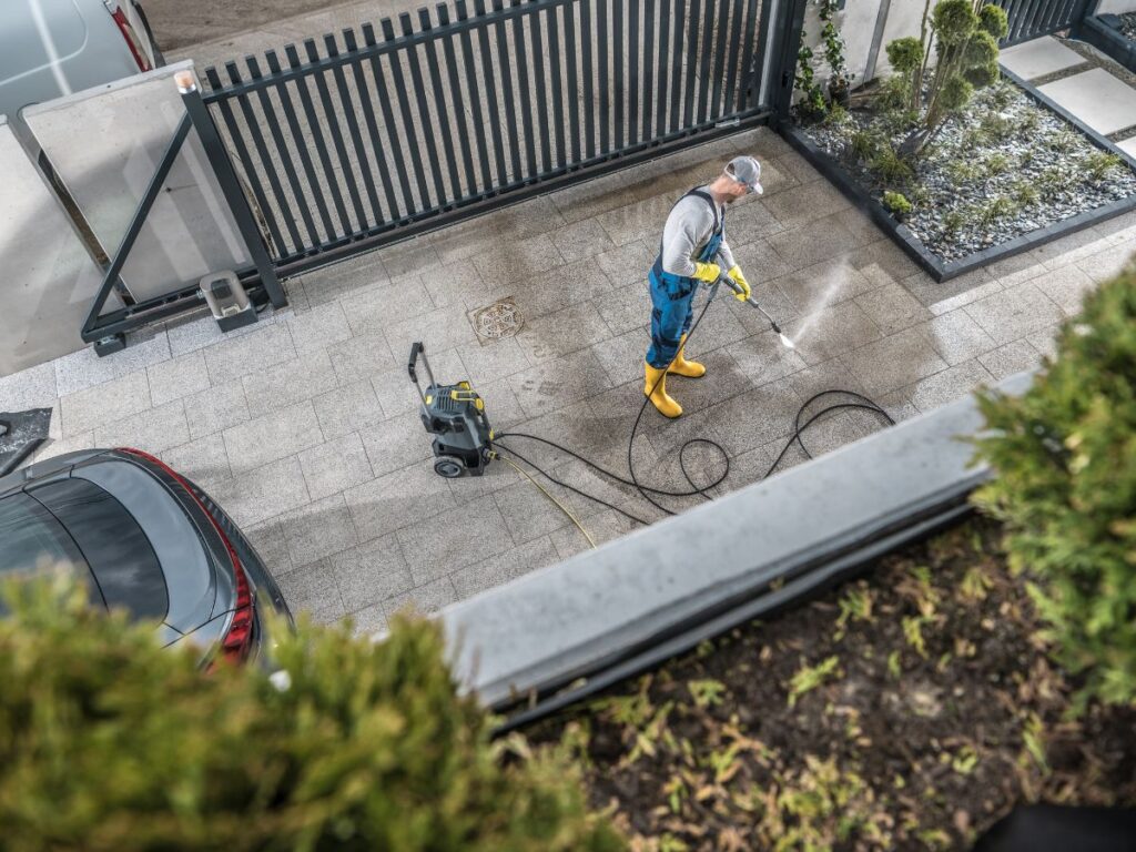 Overhead view of worker pressure washing a patio area.