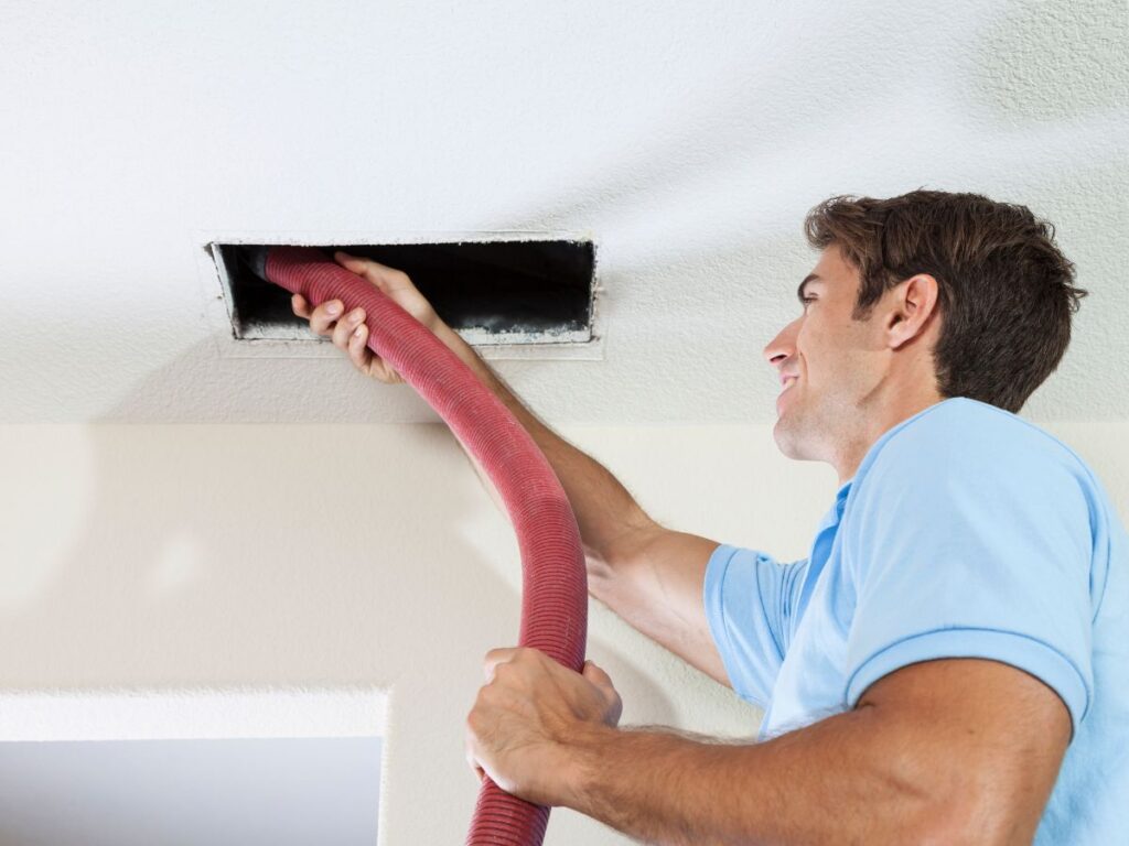 HVAC Duct Cleaning vs Air Duct Cleaning: What's the Difference and Which Does Your Home Need? 2 Worker inserting hose into wall vent for duct cleaning.